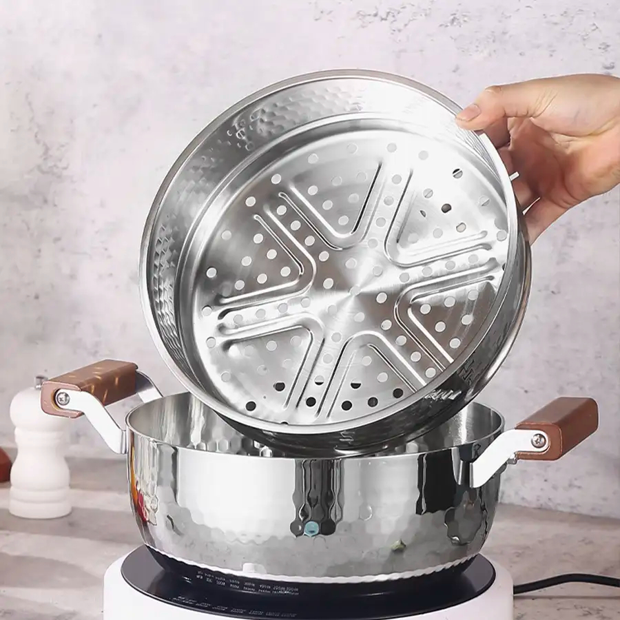 A person is lifting a stainless steel pot over a stove, ready to start cooking.
