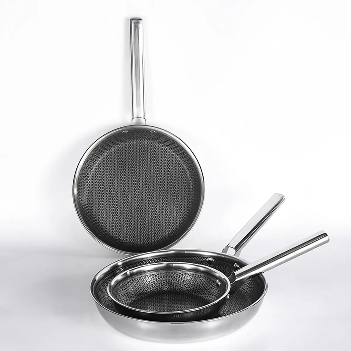 A trio of stainless steel frying pans displayed on a white background.