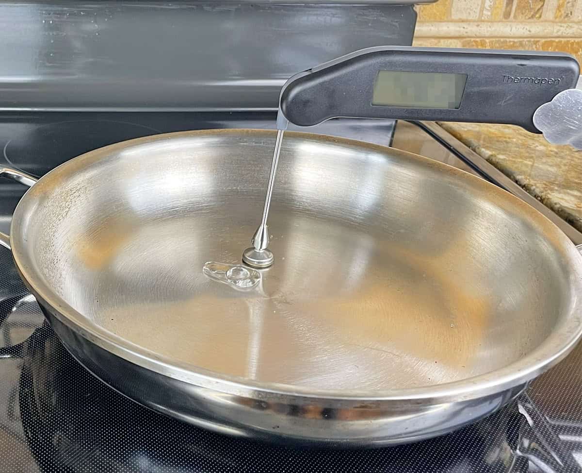 Water droplet beading up and rolling across preheated stainless steel pan surface demonstrating Leidenfrost effect at correct cooking temperature