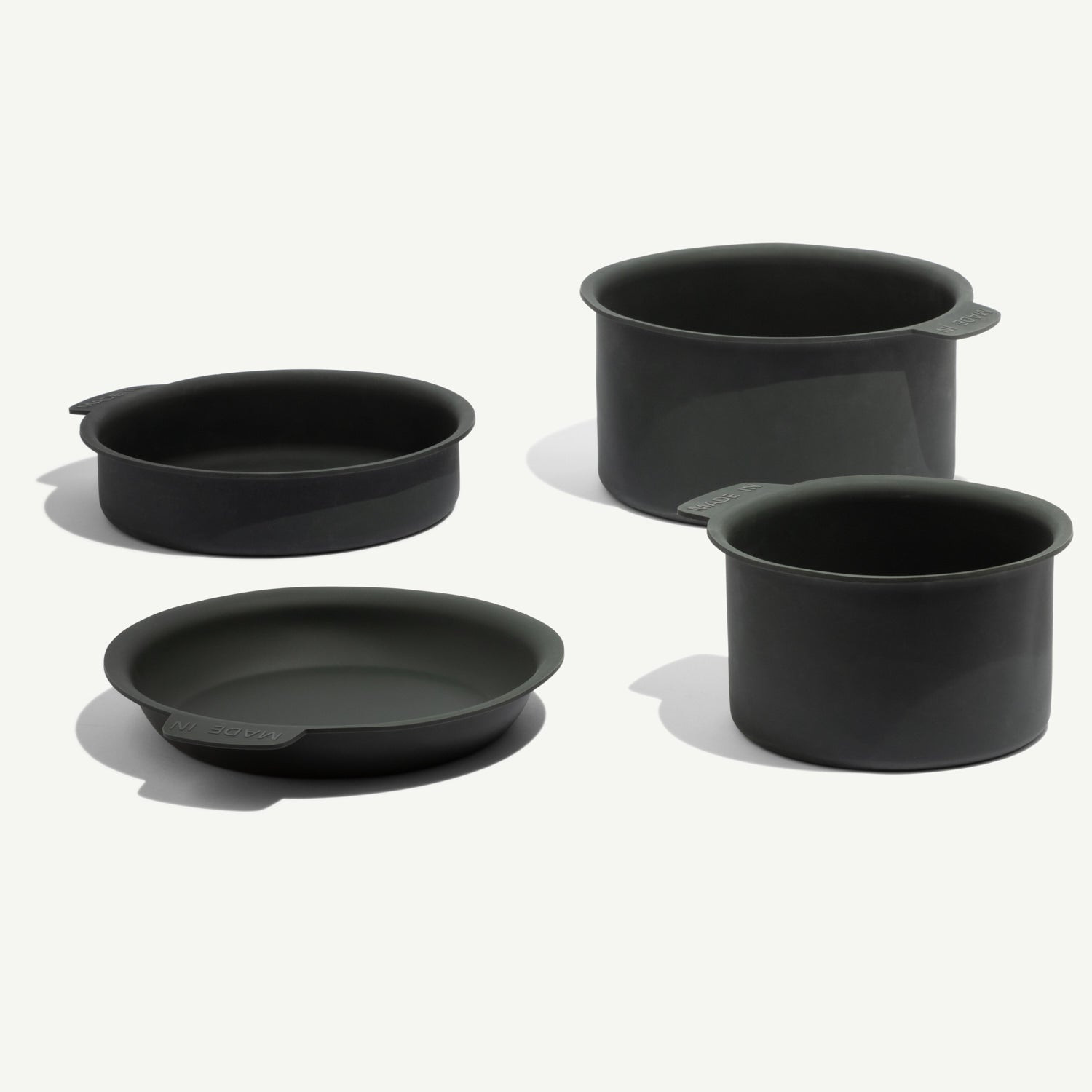 Stainless steel cookware stacked in a kitchen cabinet with fabric pan protectors between each pan to prevent scratching