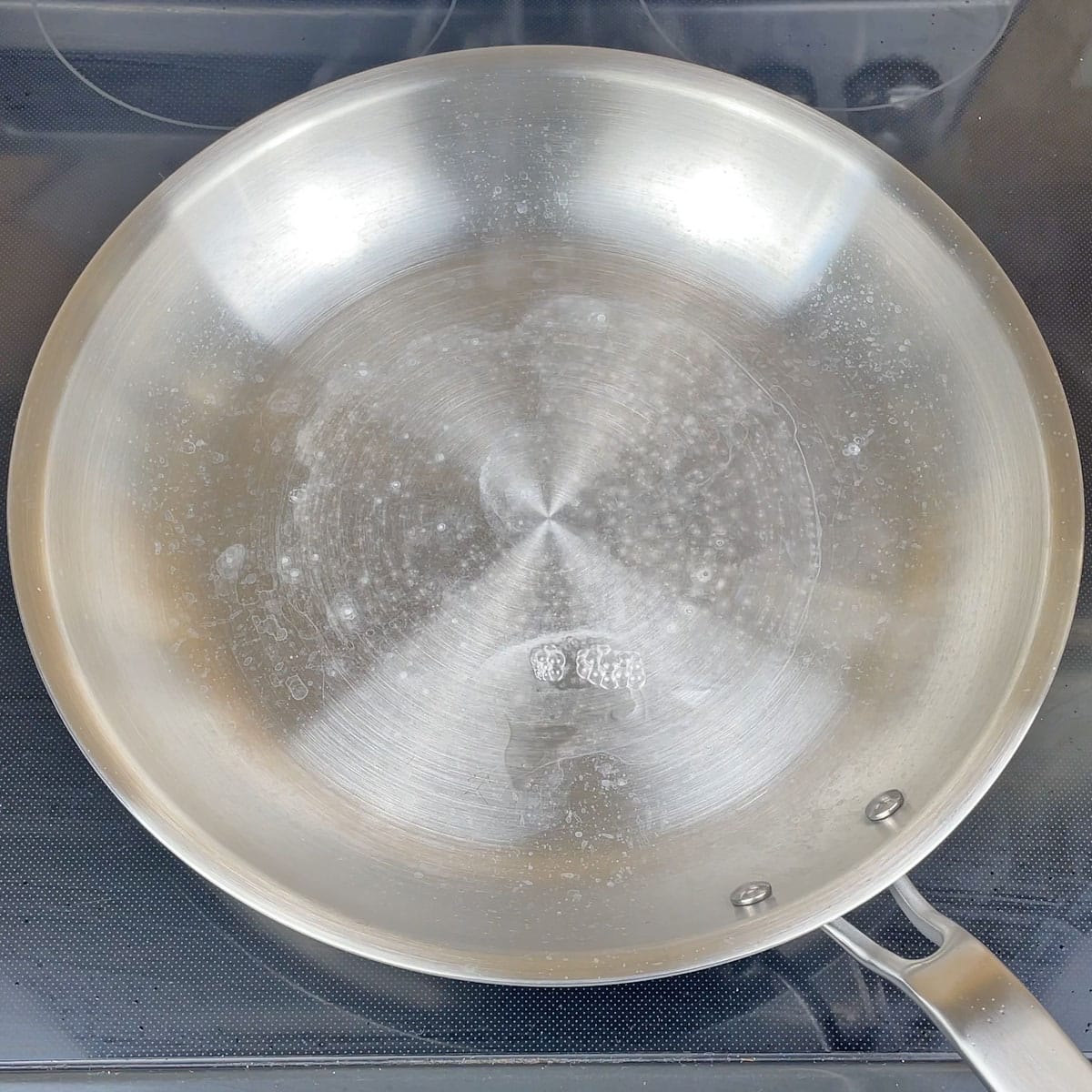 White chalky calcium mineral deposits on the inside of a stainless steel saucepan after boiling water