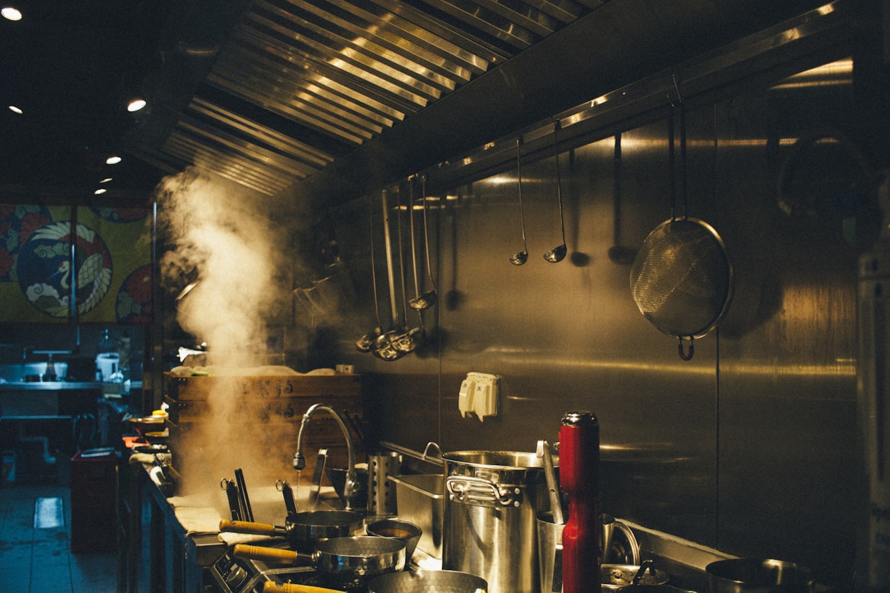 Professional commercial kitchen chef using thick disc bottom stainless steel stockpot on industrial gas range — showing practical use case for encapsulated base cookware