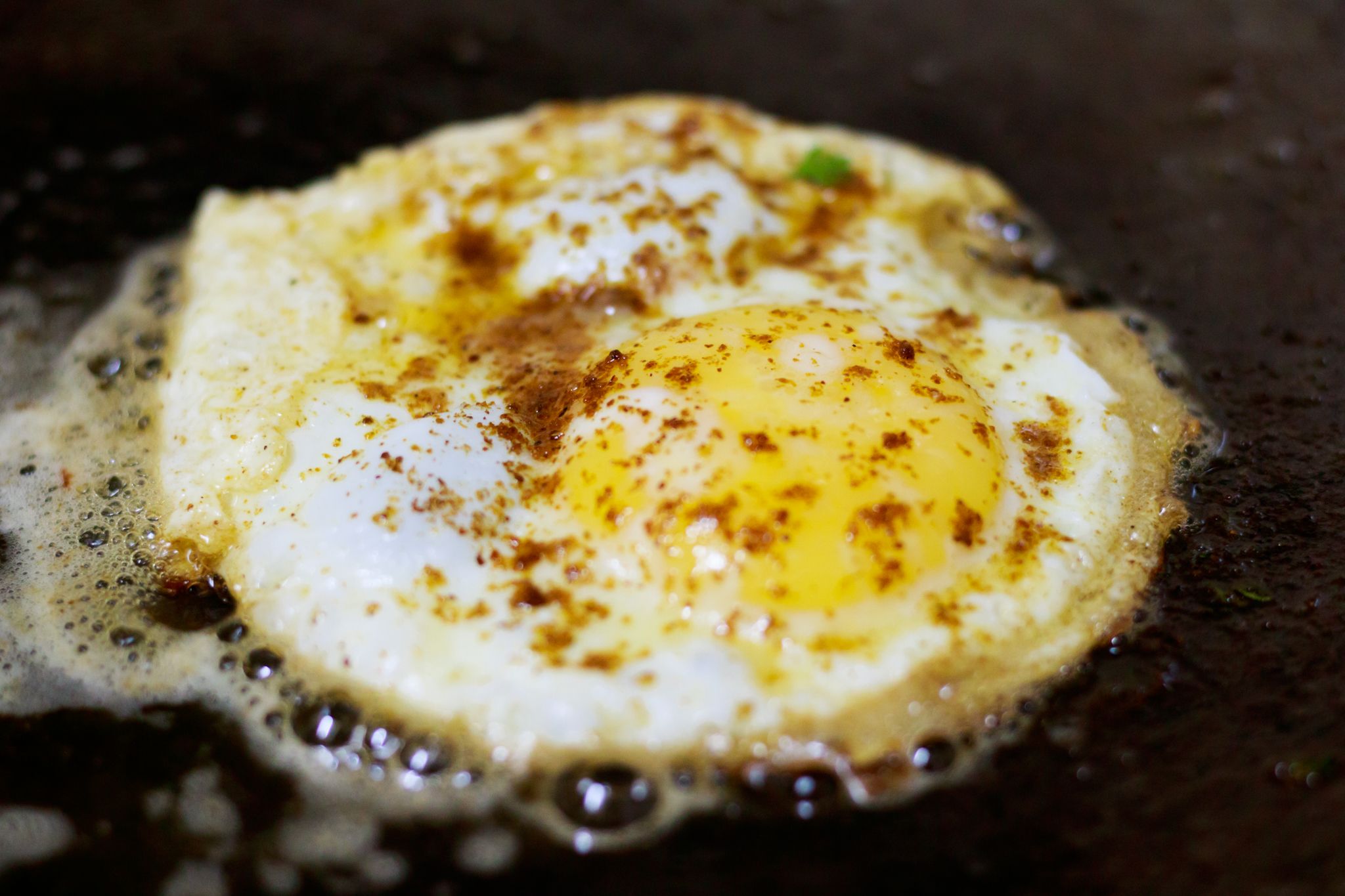 Perfectly fried sunny-side-up egg in stainless steel skillet with lacy golden edges and intact yolk showing ideal results from proper preheating technique