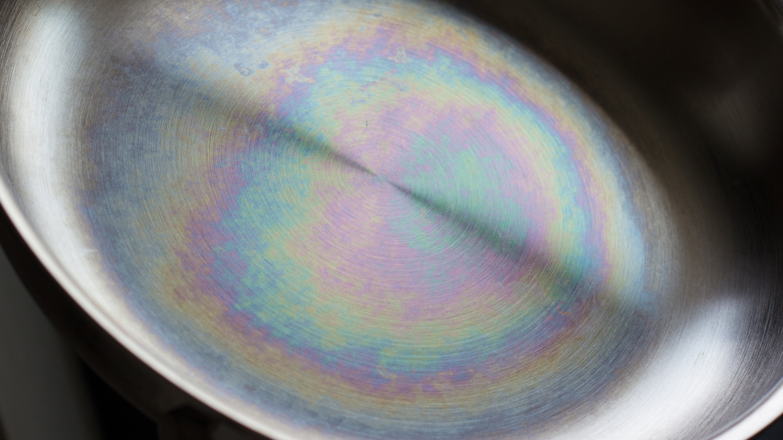 Stainless steel pan showing rainbow iridescent heat tint discoloration on the bottom from high heat exposure