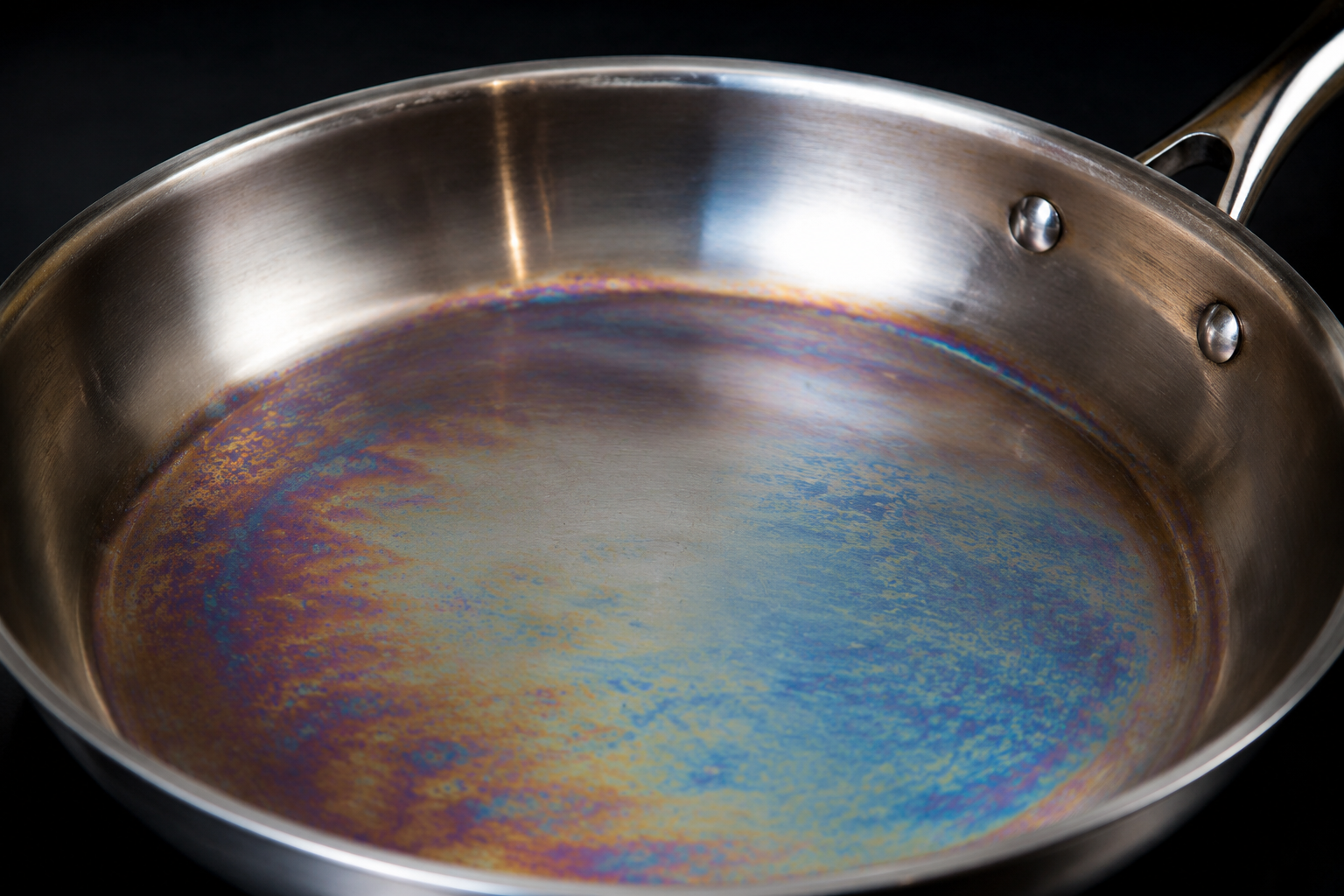 Rainbow iridescence discoloration on stainless steel pan interior - heat tint not permanent damage