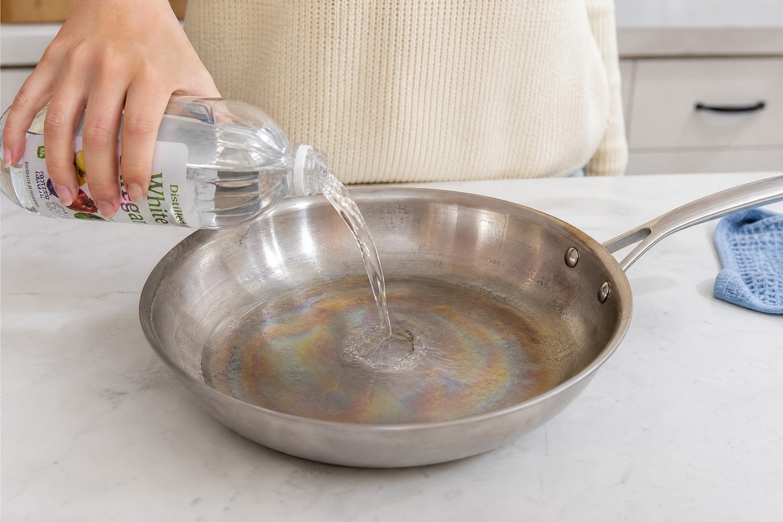Pouring white vinegar into stainless steel pan to remove rainbow heat tint discoloration