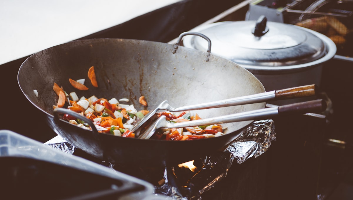 carbon steel wok and stainless steel wok side by side comparison - showing different surface texture and color