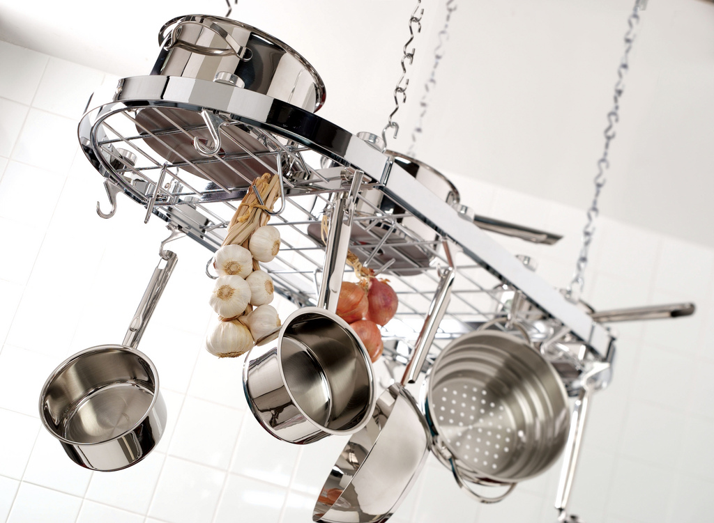 Stainless steel pans hanging on a ceiling-mounted pot rack in a home kitchen - S-hooks, isolated pieces, no surface contact