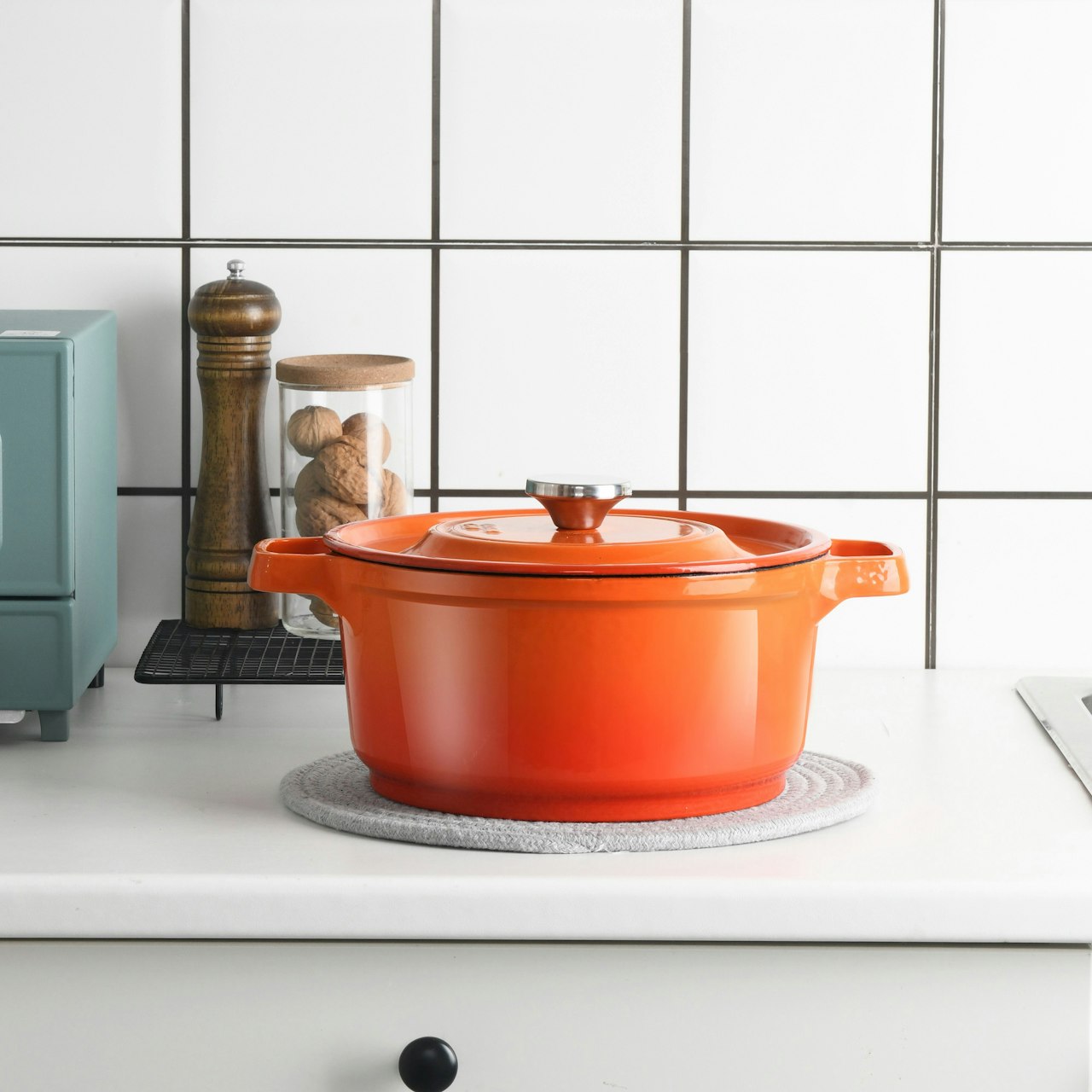 Four cookware types side by side - non-stick pan, stainless steel pot, cast iron skillet, titanium pan on clean background