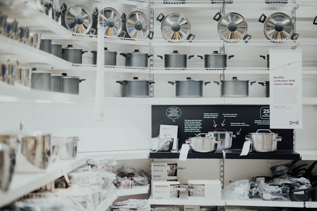 Stainless steel cookware set arranged on a professional kitchen counter - showing tri-ply construction and all-metal handles