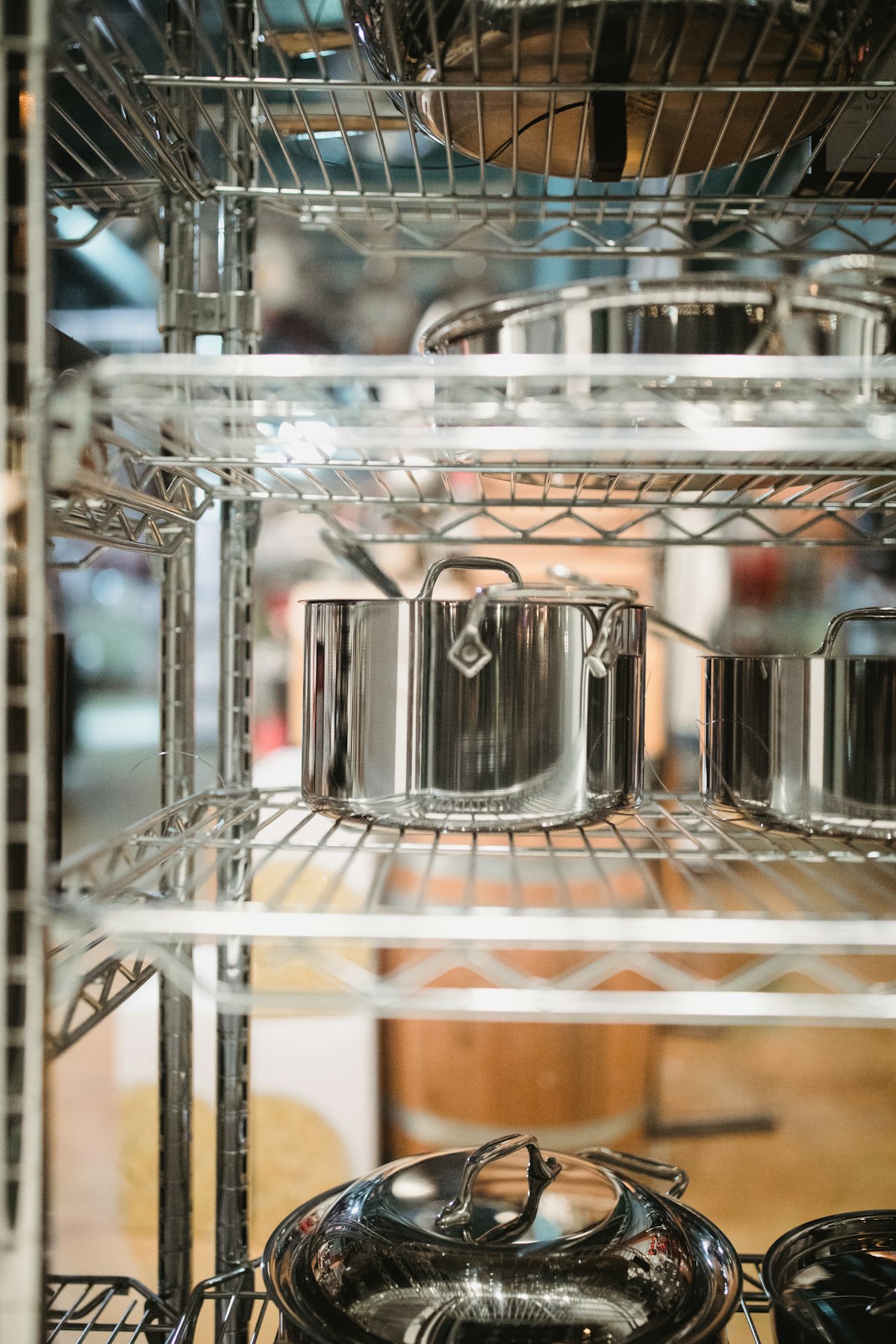 Stainless steel cookware hanging on kitchen pot rack — ideal storage method for preventing scratches and moisture buildup