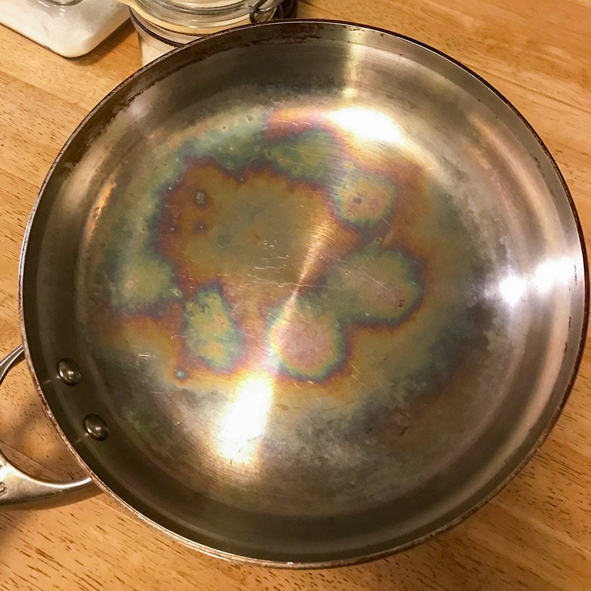 Stainless steel pan showing rainbow iridescent heat tint discoloration from high temperature exposure - characteristic straw to blue oxide layer