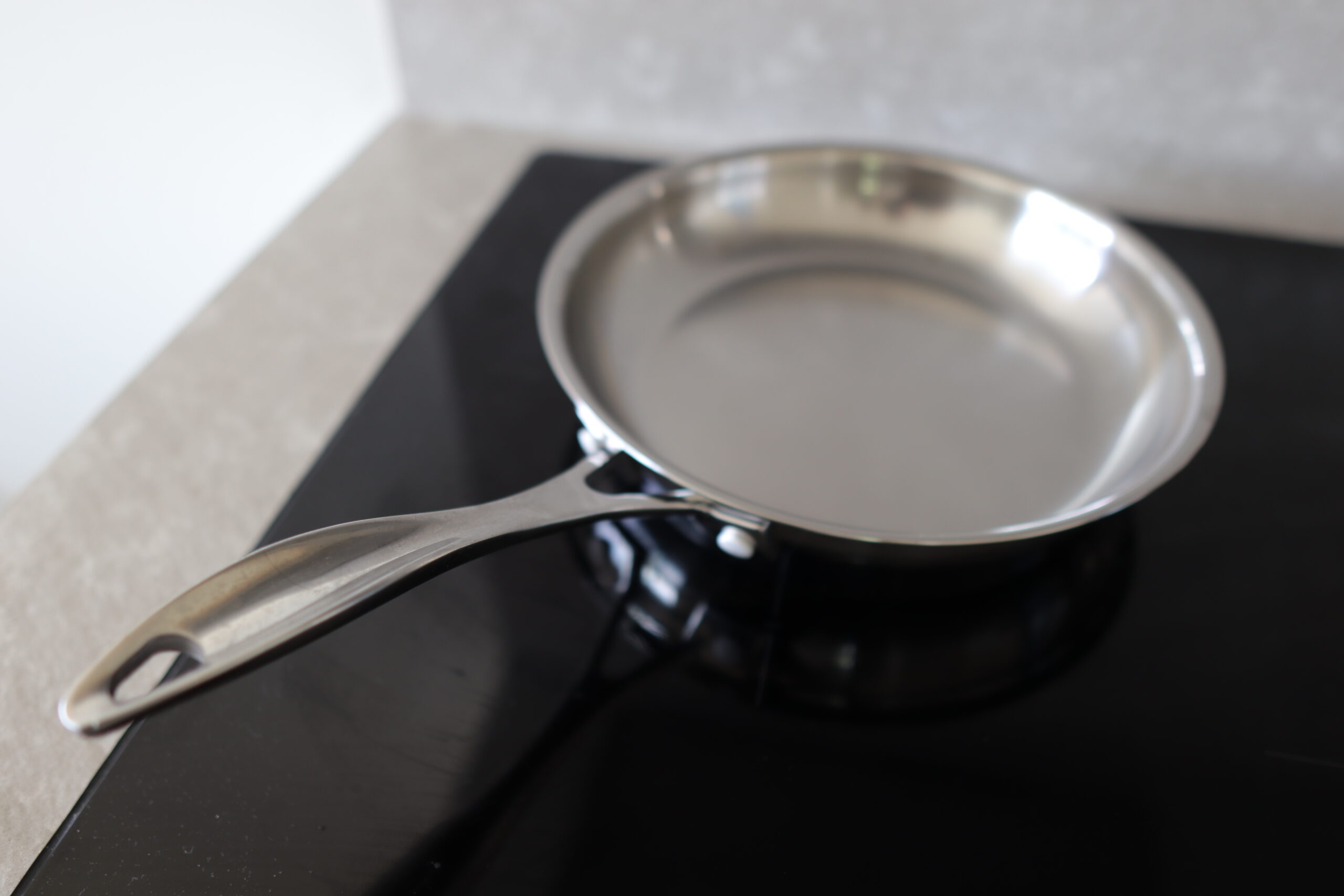 Cross-section of 18/10 stainless steel pan showing tri-ply construction with aluminum core - professional cookware material detail