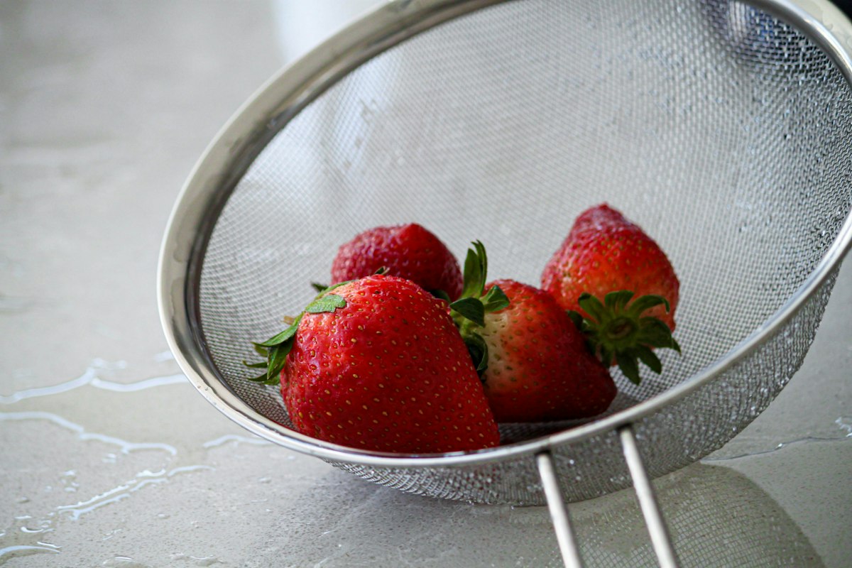 Stainless steel fine mesh strainer with strawberries - demonstrating fine filtration in kitchen use